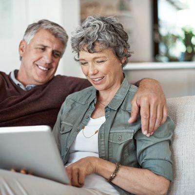 一对在沙发上放松的成熟夫妇正在使用数码平板电脑